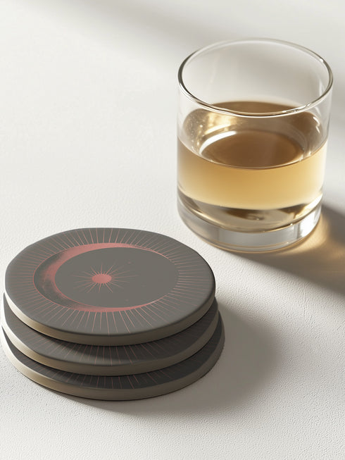 A round ceramic plate with a sleek design featuring a crescent moon and radiating lines in a muted red and black color scheme. The plate is set against a warm brown background with soft lighting, highlighting the celestial and minimalist aesthetic of the piece.